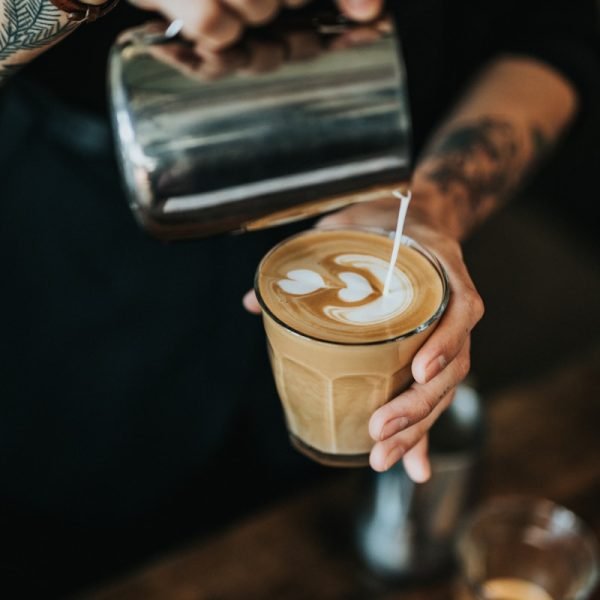 man pouring milk in coffee